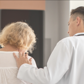 Photo d'un jeune soignant de dos avec la main sur l'épaule d'une femme