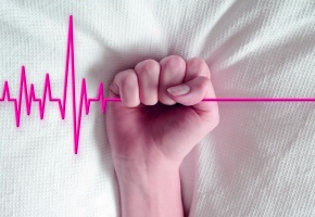 une main qui tient un dessin d'électrocardiogramme interrompu symbolisant la mort
